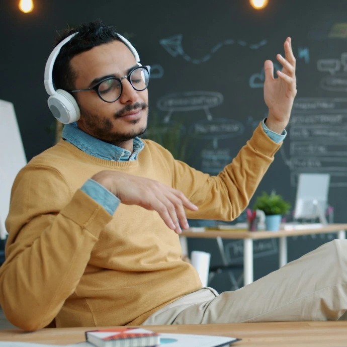 Man wearing headphones enjoys music in office.